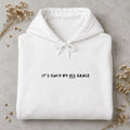 Folded white hoodie with black It's only by His grace chest lettering